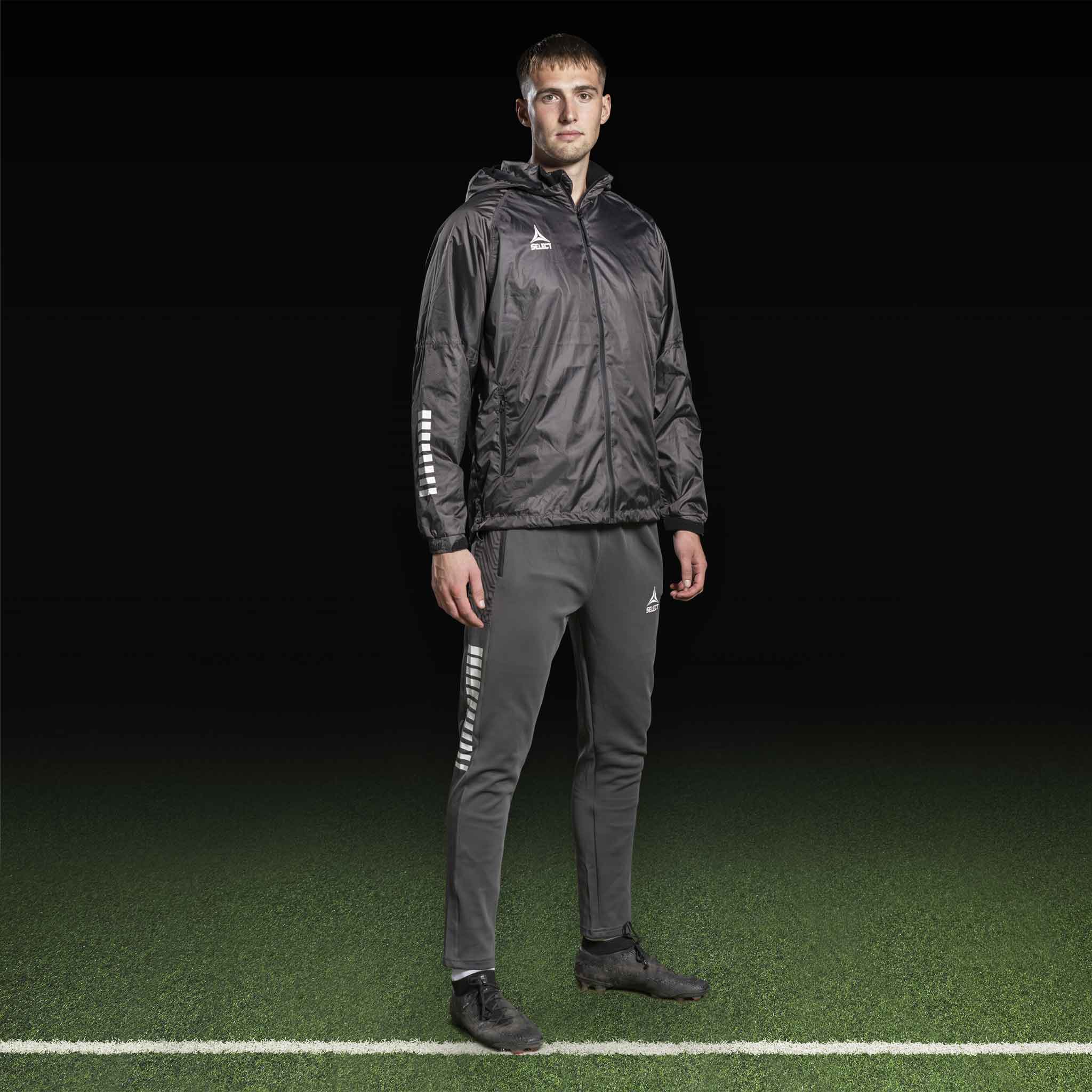 Mandlig fodboldspiller i grå Training pants Regular Fit Monaco v24 og sort jakke, Match & Training wear, set forfra.