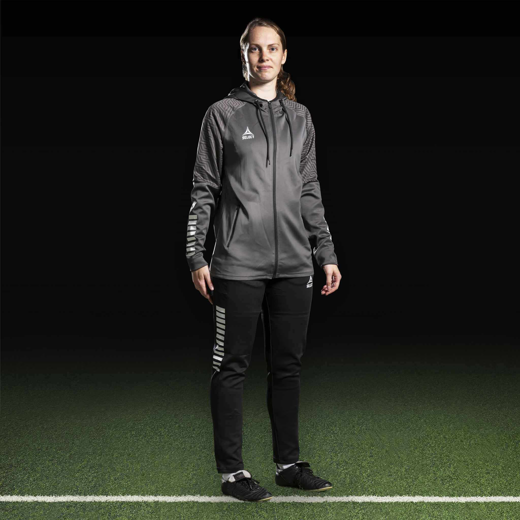 Female football player in grey Zip hoodie Monaco v24 and black pants, Match & Training wear.