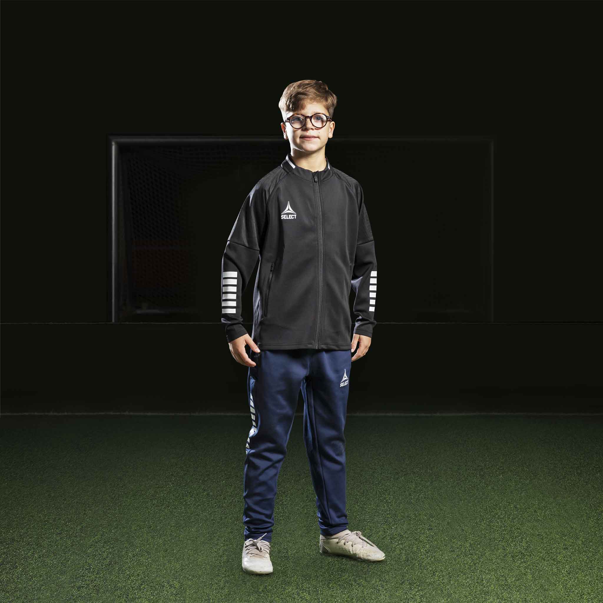 Boy football player in black Zip jacket Monaco v24 and navy pants, Match & Training wear, front view.
