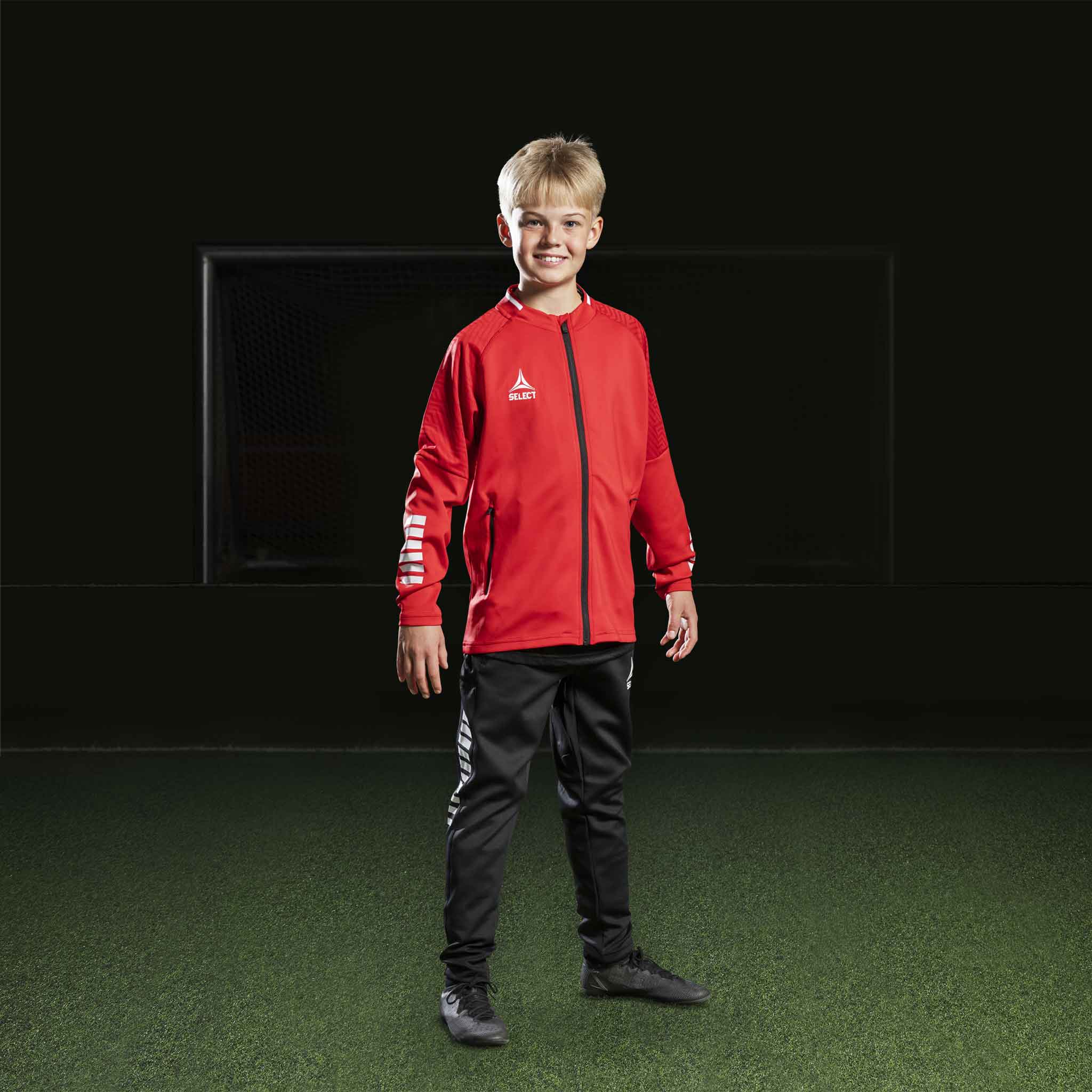 Boy football player in red Zip jacket Monaco v24 and black pants, Match & Training wear, front view.
