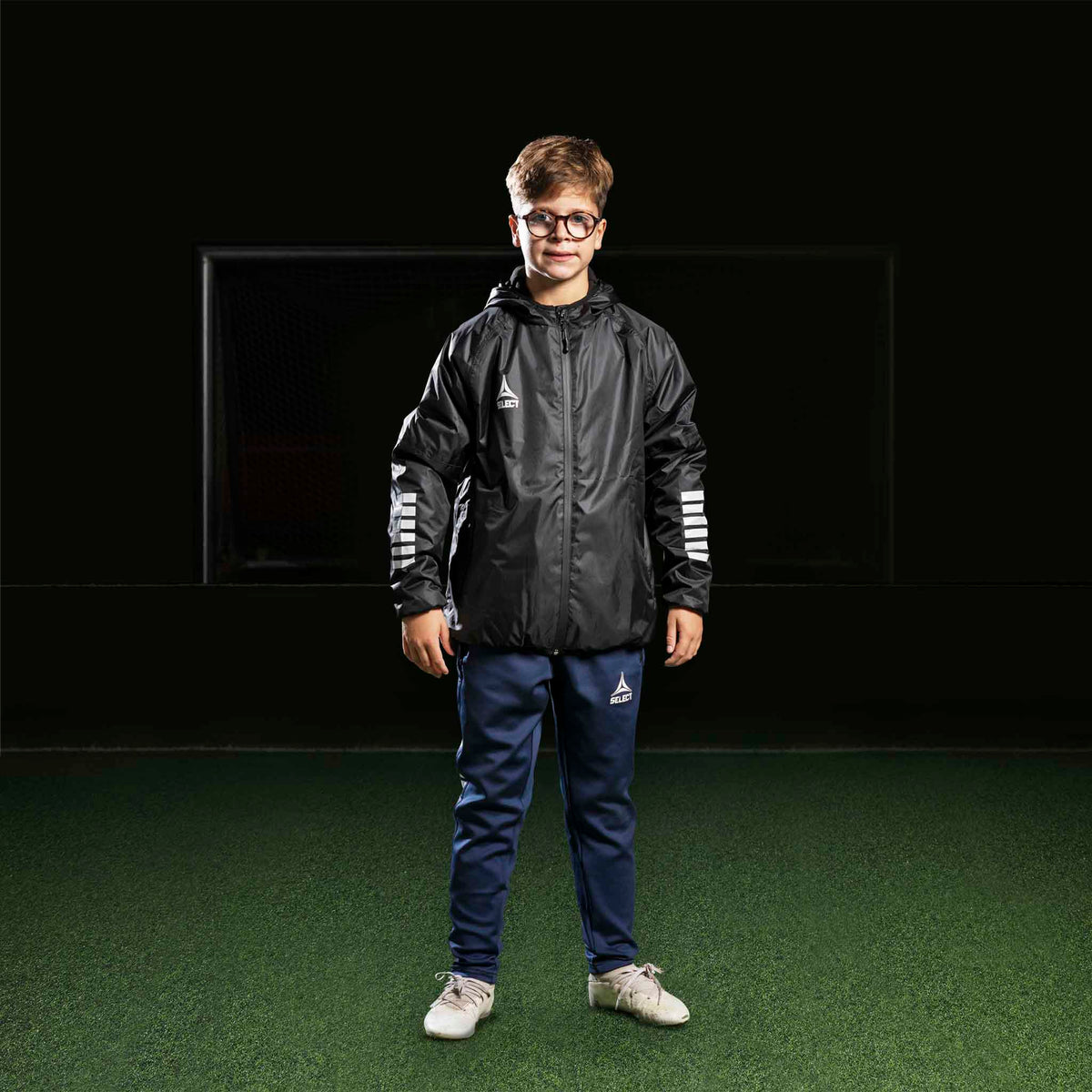 Dreng fodboldspiller i marineblå Training pants Regular Fit Monaco v24, sort jakke. Kamp- og træningstøj.