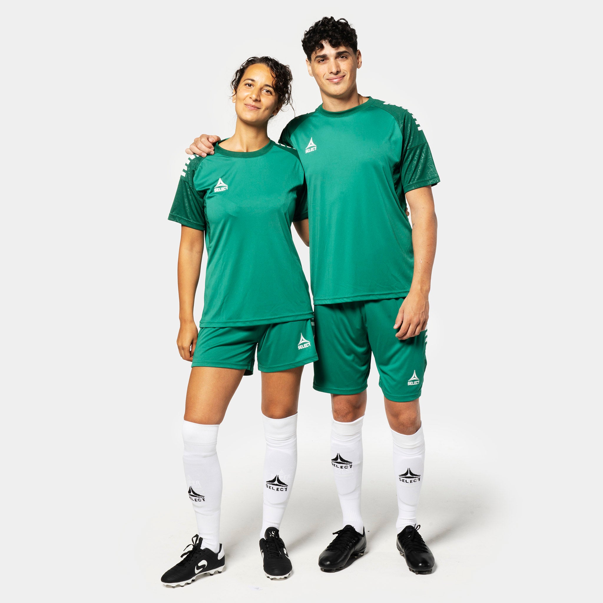 Female and male football players in green Player shorts Spain v25, Match & Training wear, with matching jerseys and white socks.