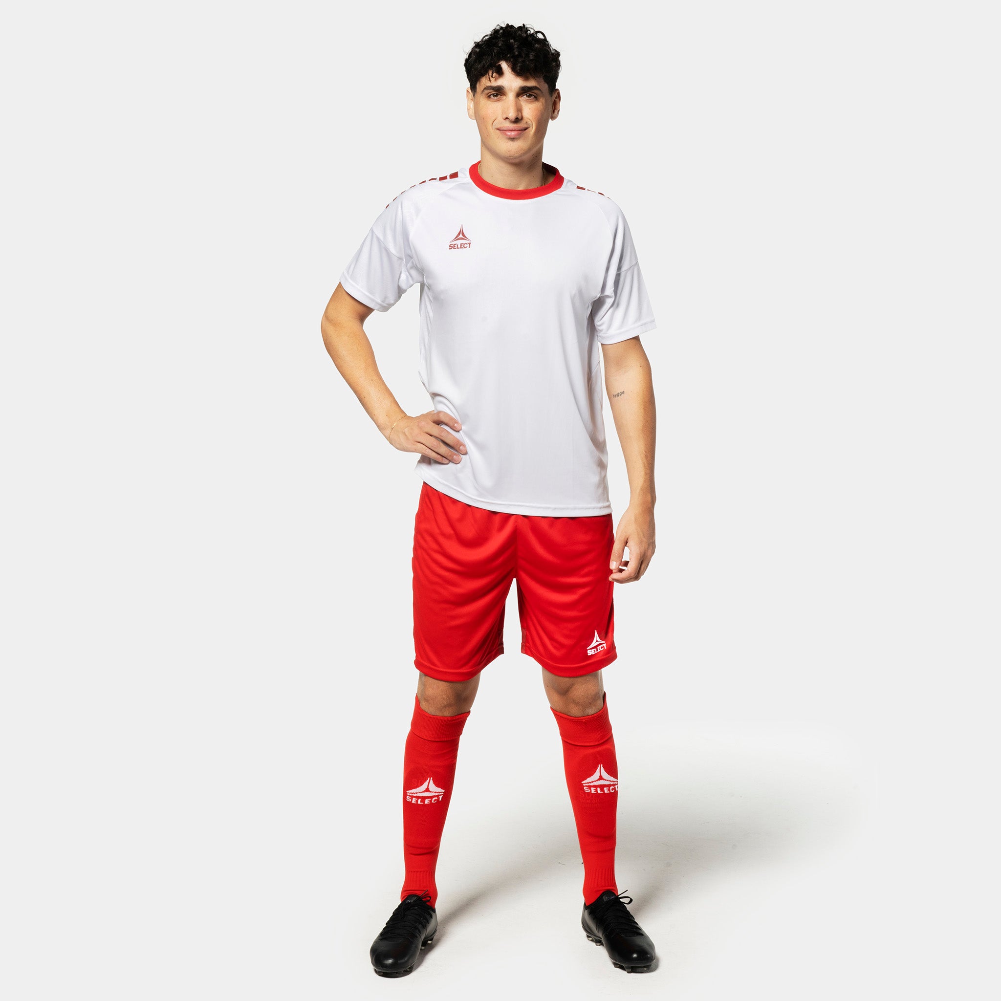 Male football player in white shirt, red Player shorts Spain v25 and red socks. Match & Training wear.