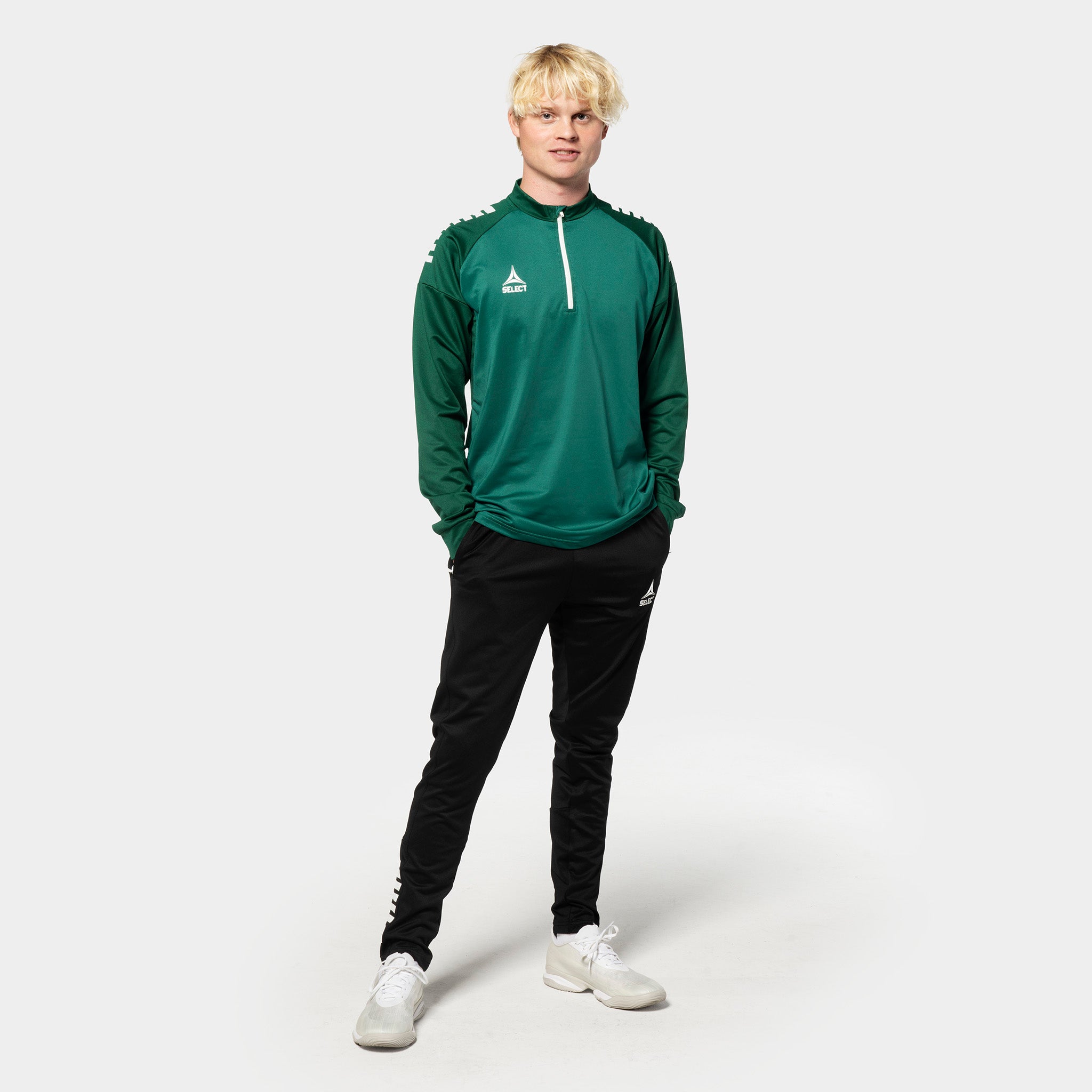 Male football player in green/white Training sweat 1/2 zip Spain v25, black pants, Match & Training wear.