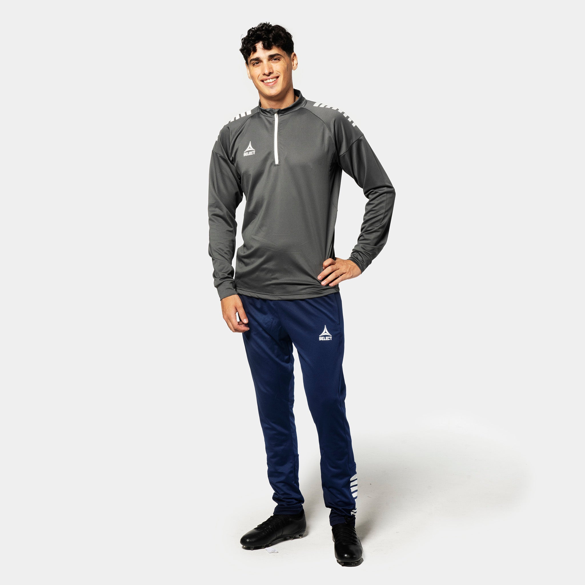 Man football player wearing grey/white Training sweat 1/2 zip Spain v25, Match & Training wear, with navy pants, front view.