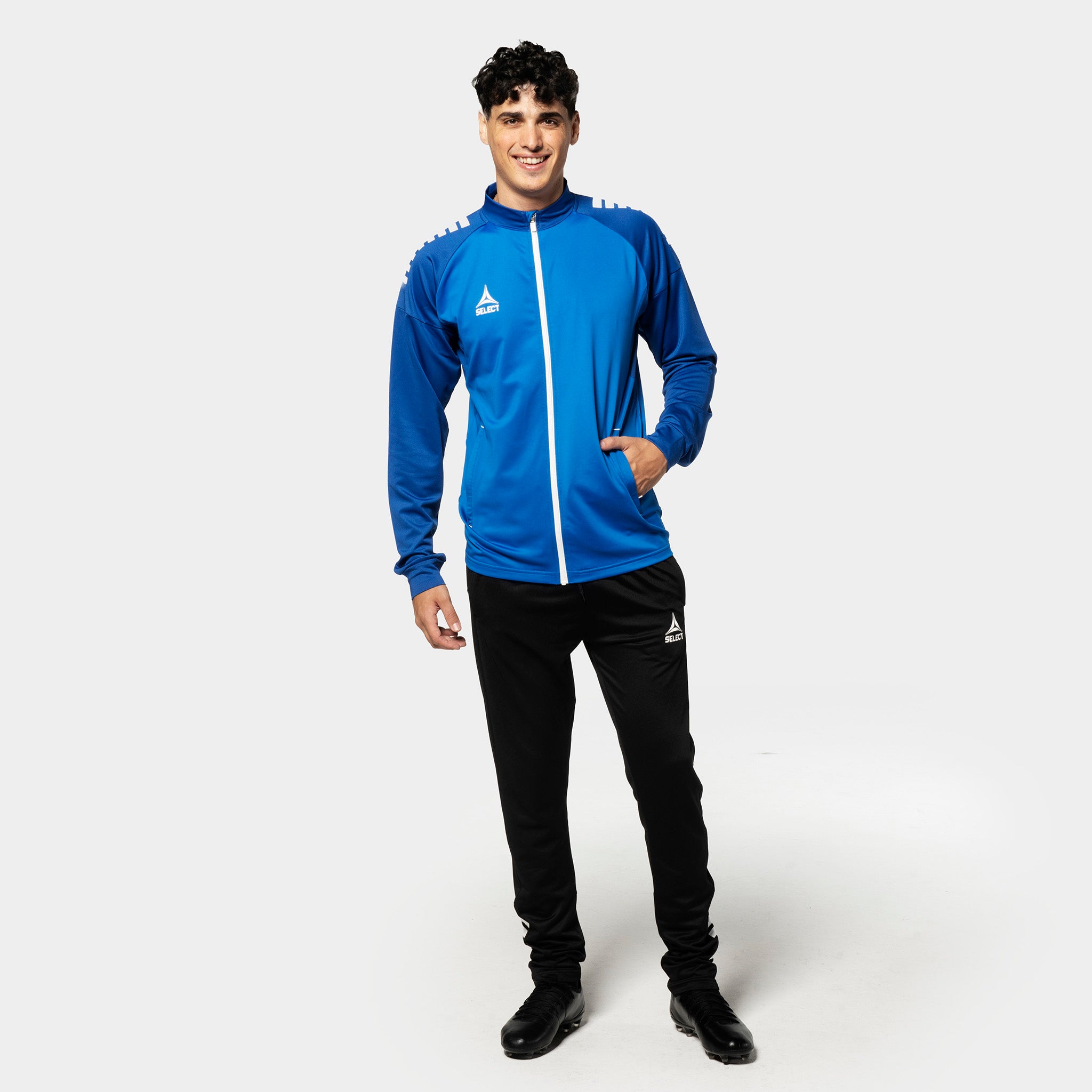 Male football player in blue and white Training zip jacket Spain v25 with black pants, Match & Training wear.