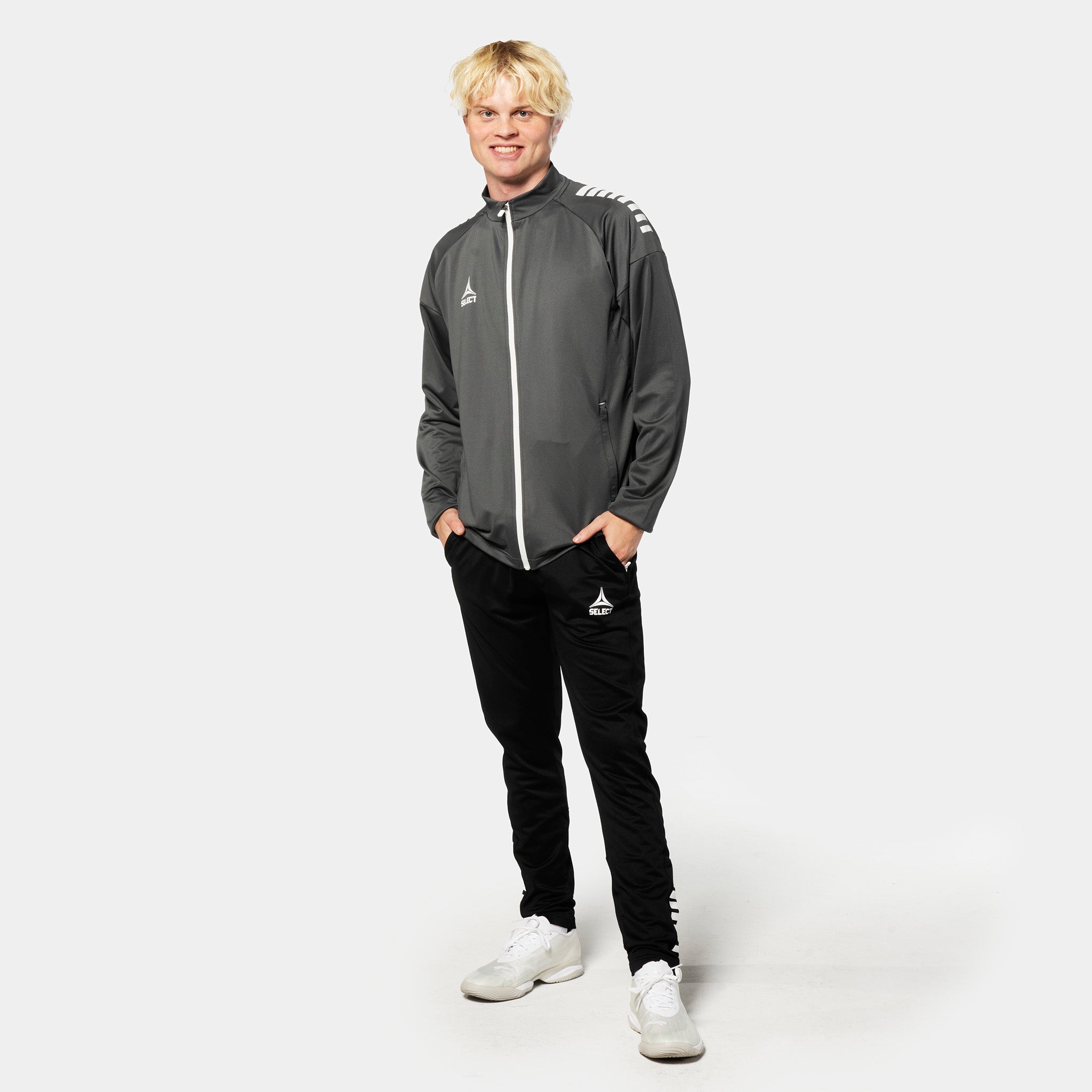 Man wears grey-white Training zip jacket Spain v25, Match & Training wear, with black pants. Football player, front view.