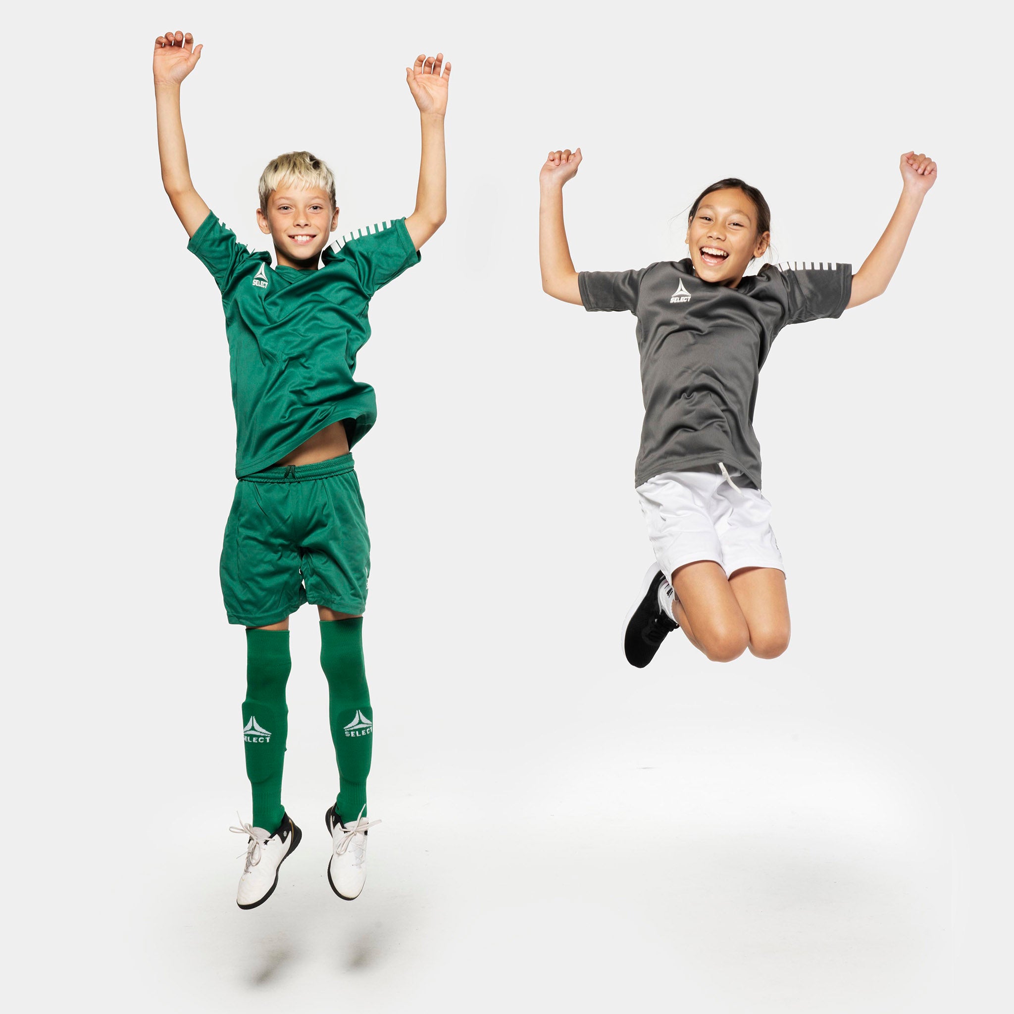 Boy and girl football players jumping in Pisa player shorts, Match & Training wear, in green and white.
