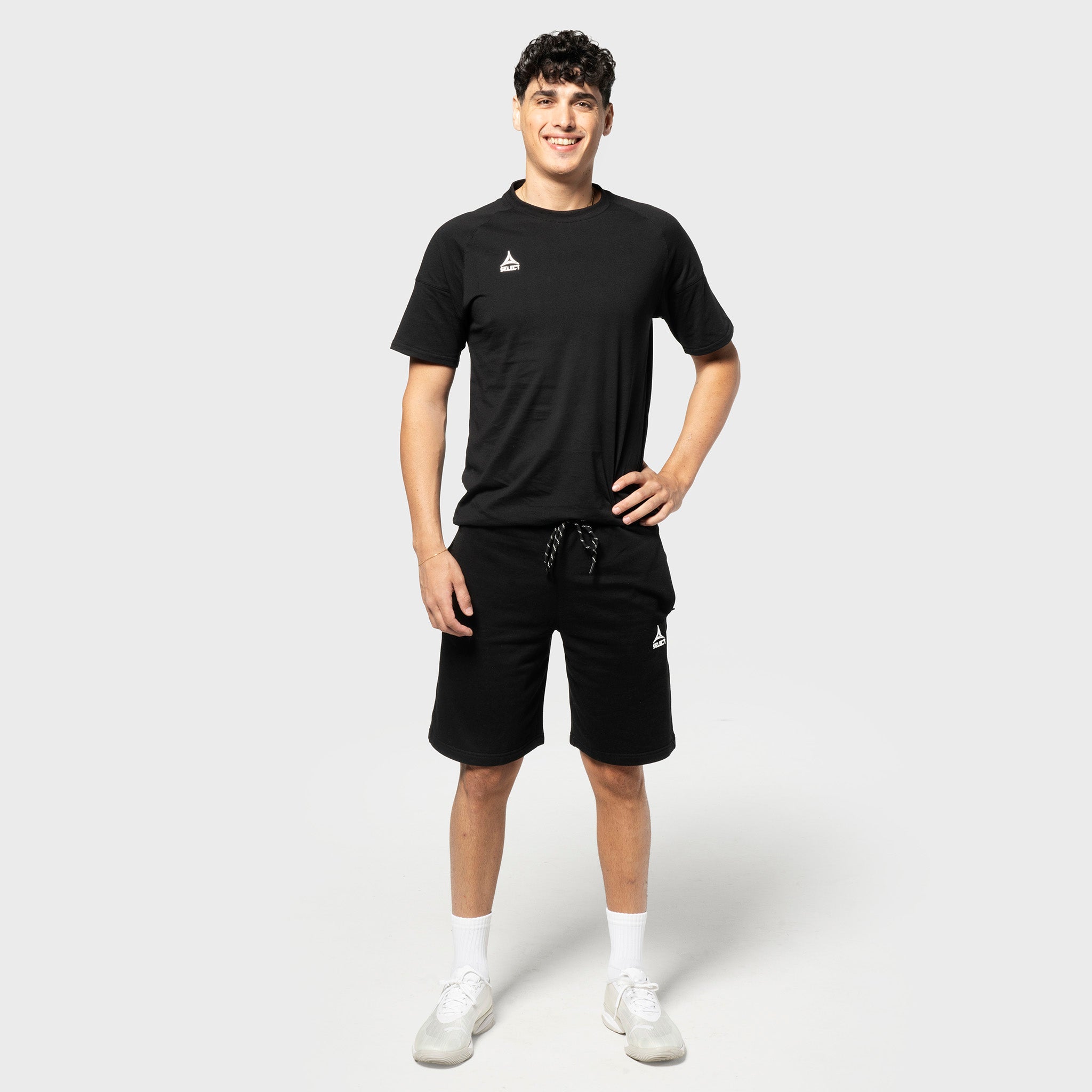 Male football player in black Sweat shorts Oxford v25 and black tee, leisure wear, front view.