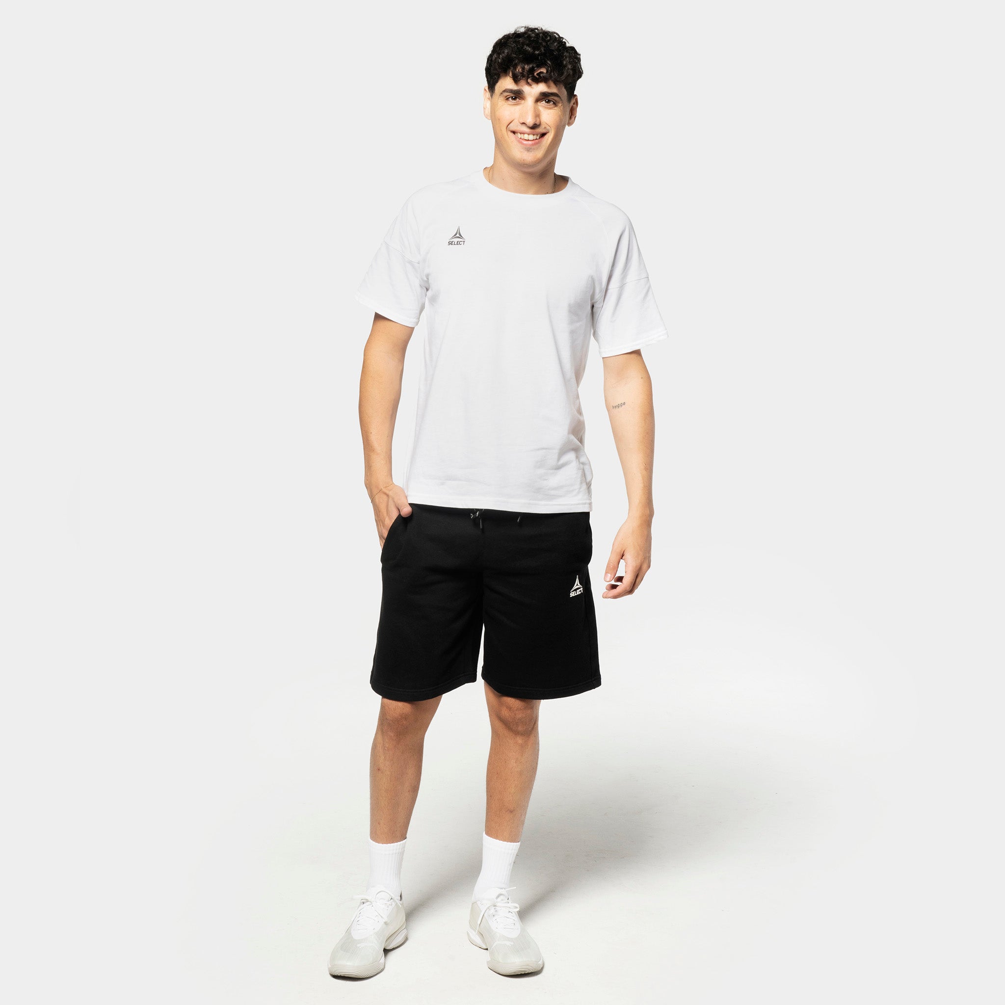 Male football player in white tee and black Sweat shorts Oxford v25, leisure wear, front view.