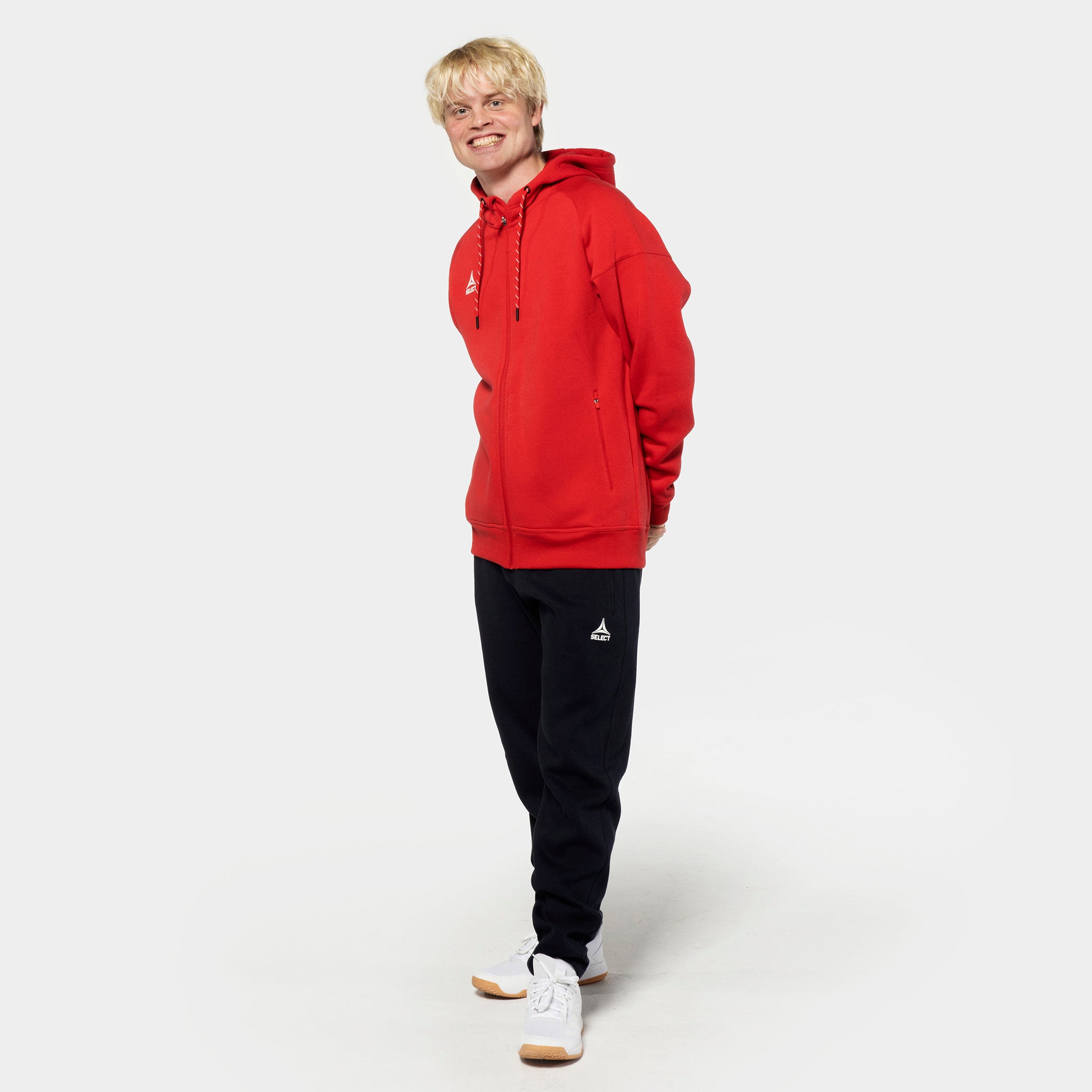 Male football player in red zip hoodie and black Sweat pants Oxford v25 leisure wear, front view.