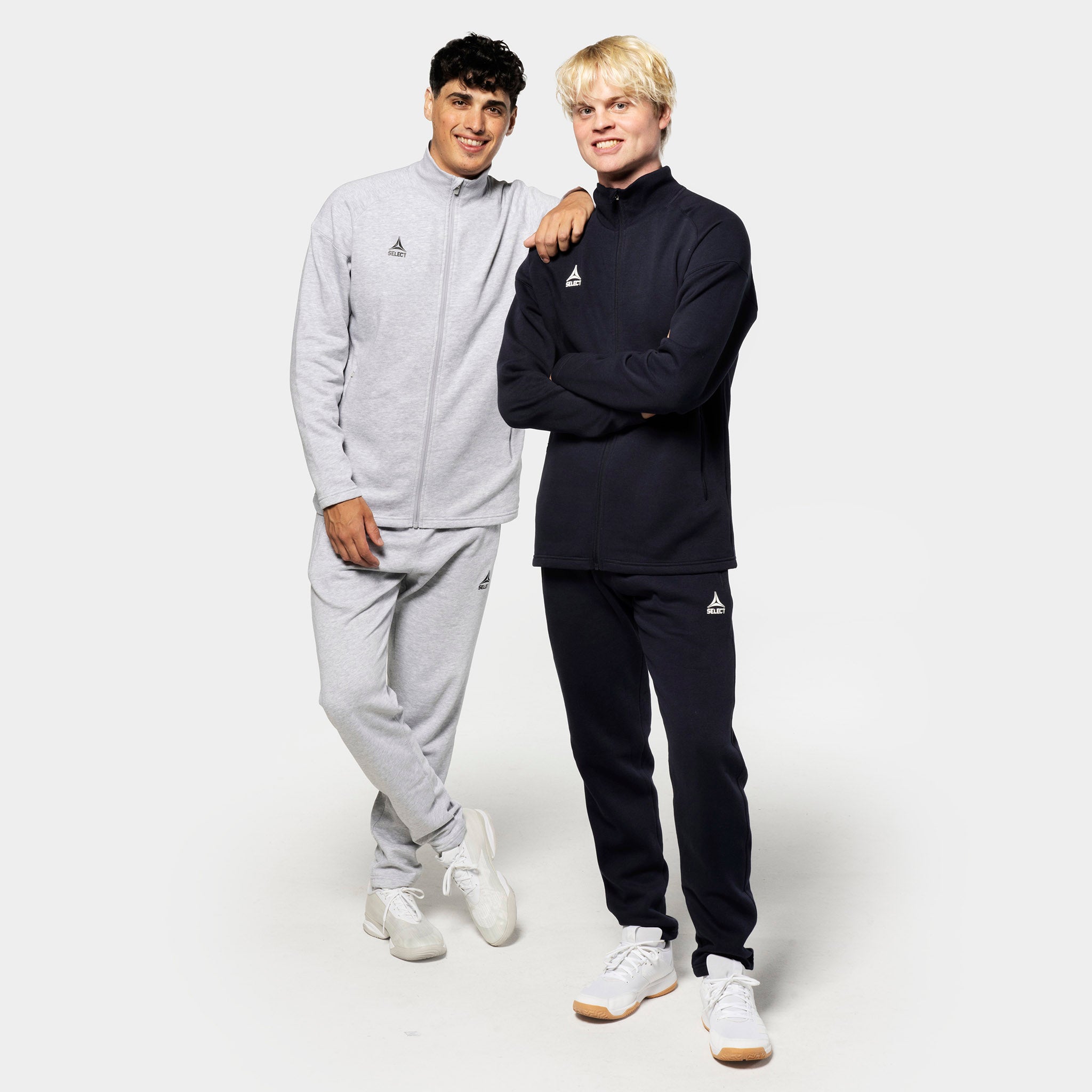 Two men model Sweat pants Oxford v25 leisure wear in grey and black, paired with matching zip jackets and white sneakers.