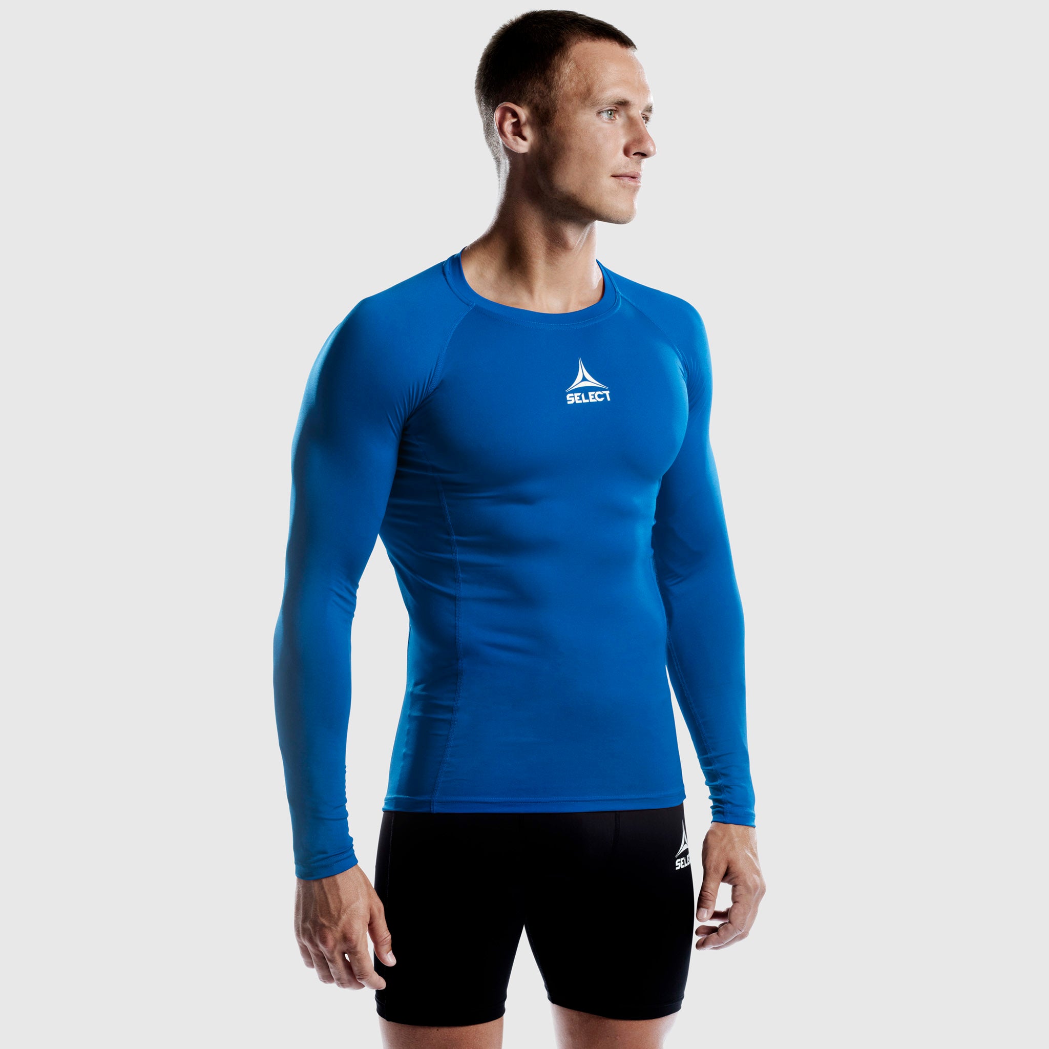 Man footballer in blue Shirts L/S Baselayer, front view, with white logo and black shorts