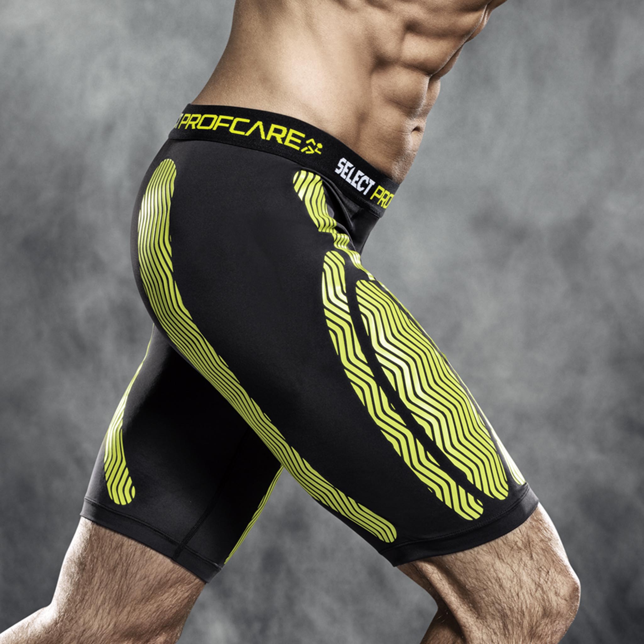 Mand iført sorte og gule Compression shorts 6407, sports support, set fra siden på model.