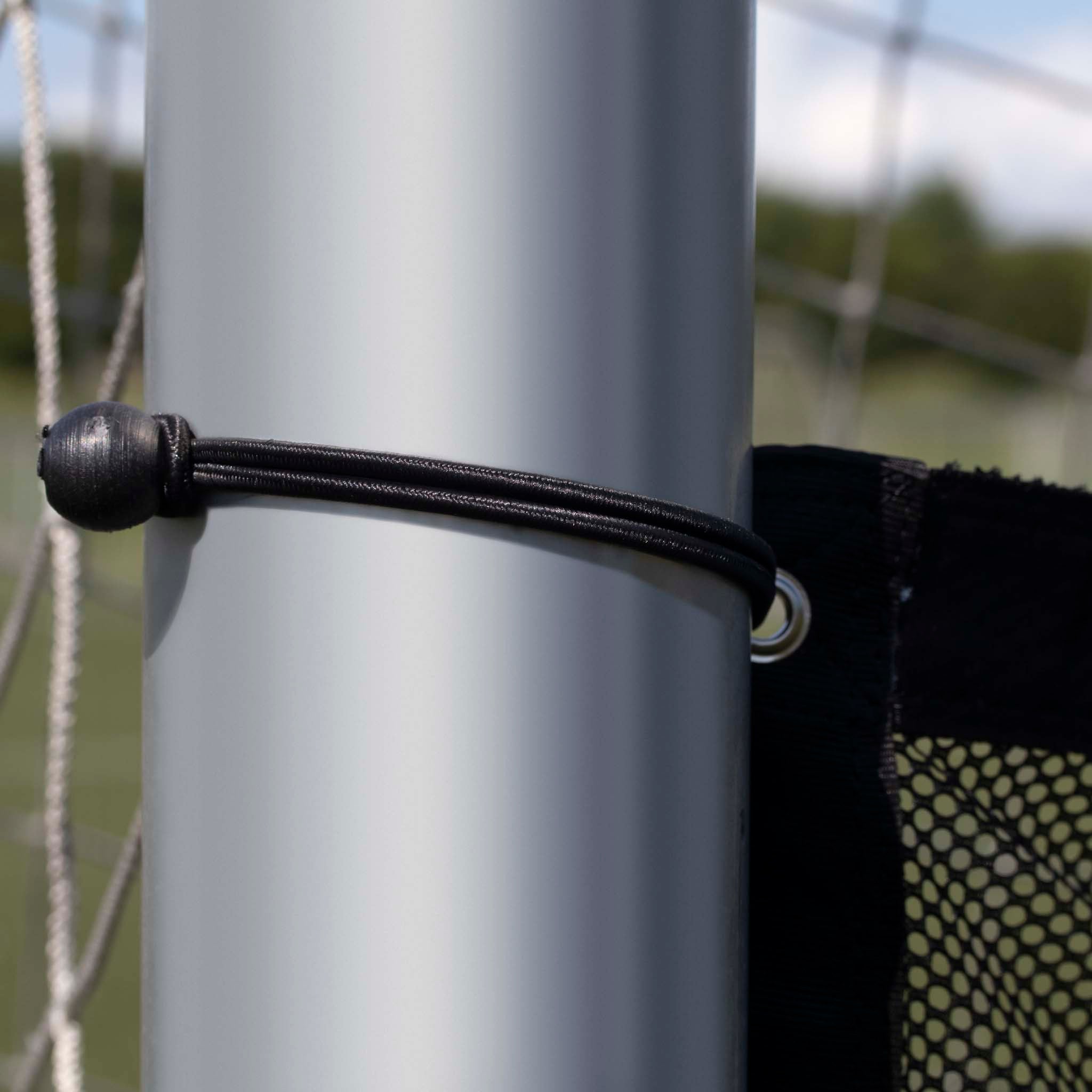 Closeup of black elastic Goal net fastener with ball-end bungee securing net to silver post, football training equipment